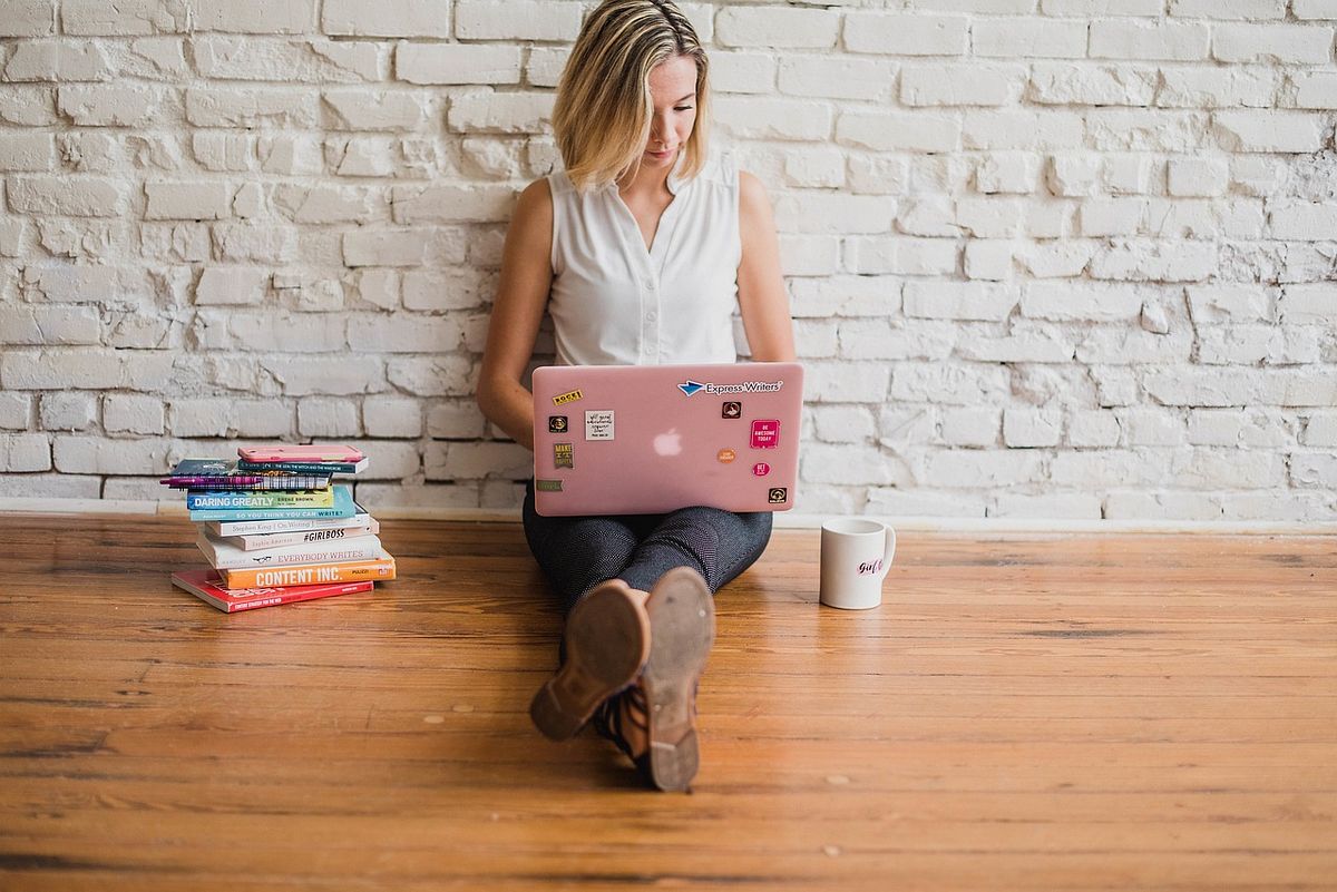 a woman with a laptop sitting on the floor typing